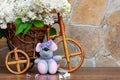A mouse sits in front of a bicycle with a bouquet of lilacs close-up.