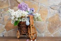 A mouse sits on a bicycle with a bouquet of lilacs close-up.