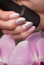 Purple neat manicure on female hands on flowers background. Nail design Royalty Free Stock Photo