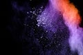 Purple orange color powder explosion cloud  on black background.Closeup of purple orange dust particles splash Royalty Free Stock Photo