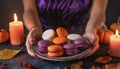 purple orange macaroons on a plate in women\'s hands