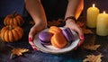 purple orange macaroons on a plate in women\'s hands