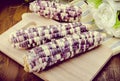 Purple organic corn on cob on wooden background Royalty Free Stock Photo