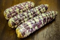 Purple organic corn on cob on wooden background Royalty Free Stock Photo