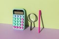 Purple pen, calculator and magnifying glass on a green purple background Royalty Free Stock Photo