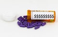 Purple pills spilling our of prescription bottle with dollar signs on it Royalty Free Stock Photo