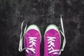 purple-pink-lilac sneakers with untied laces on a dark concrete background. Copy space. View from above