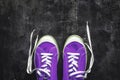 purple-pink-lilac sneakers with untied laces on a dark concrete background. Copy space. View from above
