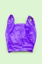 Purple plastic bag on green background. Environment pollution concept Royalty Free Stock Photo