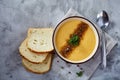 Porcelain bowl of pumpkin soup on napkin over white textured background, close-up, selective focus, top view. Royalty Free Stock Photo