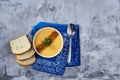 Porcelain bowl of pumpkin soup on napkin over white textured background, close-up, selective focus, top view. Royalty Free Stock Photo