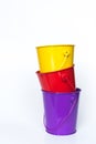 Purple, red, and yellow metal pails stacked together solid white background Royalty Free Stock Photo