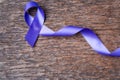 Purple ribbon for the awareness about the unacceptability of the violence against women on dark gray rustic wooden surface. Top Royalty Free Stock Photo