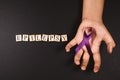 Purple ribbon on cramps hand and EPILEPSY word against black background. Royalty Free Stock Photo