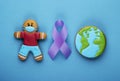 purple ribbon and gingerbread boy and planet earth on blue background. world day of fight against cancer Royalty Free Stock Photo