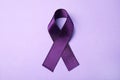 Purple ribbon on lilac background. Domestic violence awareness