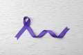 Purple ribbon on white wooden background. Domestic violence awareness