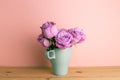 Purple rose flowers in ceramic cup on wooden table with pink background Royalty Free Stock Photo