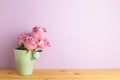 Purple rose flowers in cup on wooden table with purple background Royalty Free Stock Photo