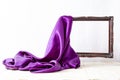 Purple satin fabric unveiling a levitating wooden empty frame