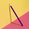 Purple school pencil on a yellow pink background. Modern conceptual art.