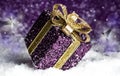 Purple shiny gift with a gold bow, on a snowy background