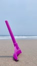 Purple little shovel toy at beach white sand blue sky little wave