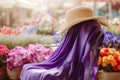 purple silk scarf on a chair with a sun hat, flower market in soft focus behind Royalty Free Stock Photo