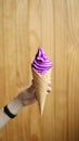 Purple softserve with hand on wooden background