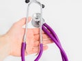 Purple stethoscope in doctor`s hand on white background. Close-up.