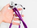 Purple stethoscope in hand of doctor on white background isolation. Medicine