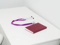 Purple stethoscope and red medical journal, notebook on white table in cabinet.