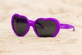 Purple sunglasses shaped heart on the sand Royalty Free Stock Photo