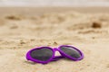 Purple sunglasses shaped heart on the sand Royalty Free Stock Photo