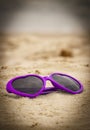 Purple sunglasses shaped heart on the sand Royalty Free Stock Photo