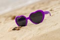 Purple sunglasses shaped heart with shells on the sand Royalty Free Stock Photo