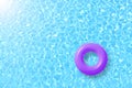 Purple swimming pool ring float in blue water and sun bright.