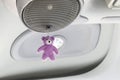 The purple teddy bear doll is hanging on the speakers in the car room Royalty Free Stock Photo