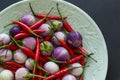 Purple Thai eggplants and hot chili peppers on a green dragon plate on a black background. Close-up, top view Royalty Free Stock Photo