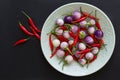 Purple Thai eggplants and hot chili peppers on a green plate and nearby on a black background. Asian food Royalty Free Stock Photo