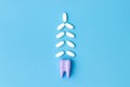 Purple tooth model and medical tablets on a blue background with copy space. Toothache pills. White Christmas tree made of pills Royalty Free Stock Photo