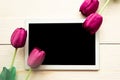 Purple tulips and black mockup tablet on wooden background.