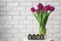 Purple tulips in a glass jar and wooden letters arranged into a word Home Royalty Free Stock Photo