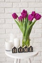 Purple tulips in a glass jar and wooden letters arranged into a word Home Royalty Free Stock Photo