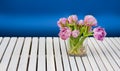 Purple tulips in the glass vase on the white wooden table and blue background Royalty Free Stock Photo