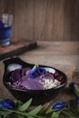 Purple vegetable salad in black bowl placed on the wood table there are glass and flower placed around