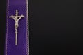 Purple violet stole with a metal cross on a black background