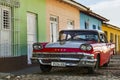 Purple and white classic American car and blue colonial building in streets of Trinidad, Cuba