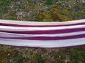 Purple and white hammock over green grass lawn