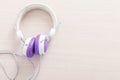 Purple and white headphone on wood table with free space for background. Music relax concept.